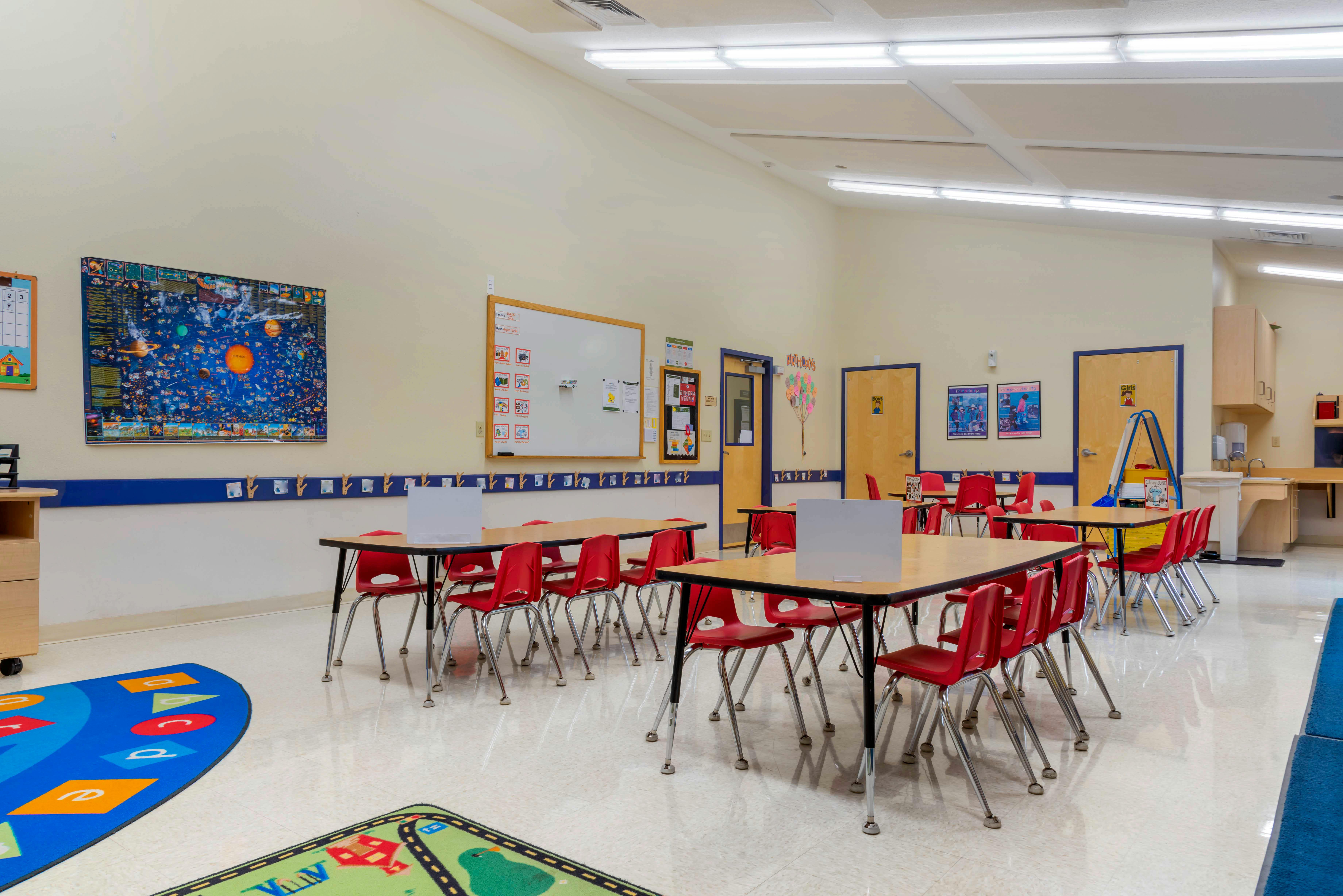 Empty classroom with small tables and red chairs