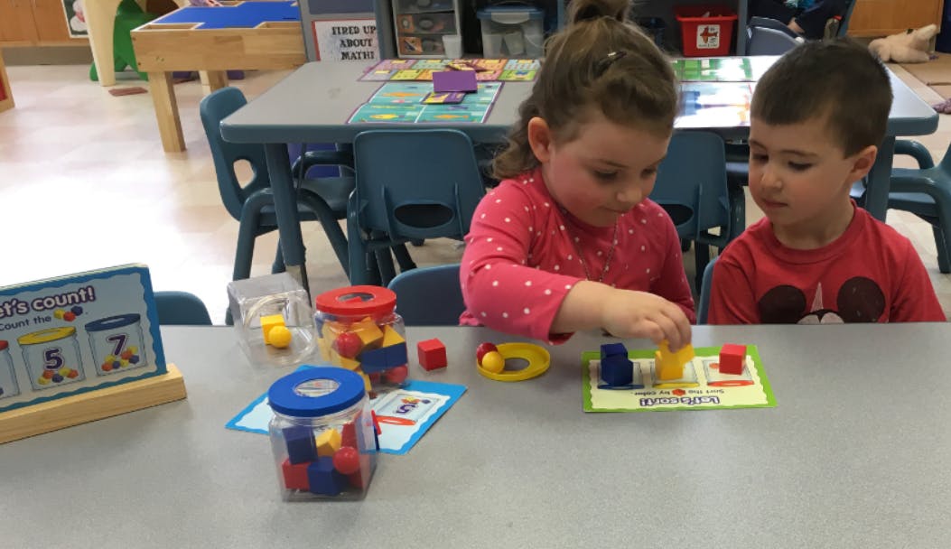 Two children playing with blocks at a table