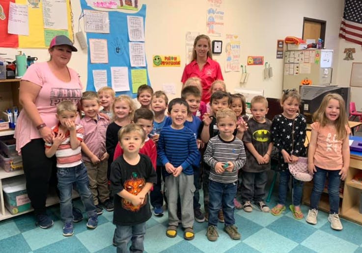 Two people with a group of children in a classroom