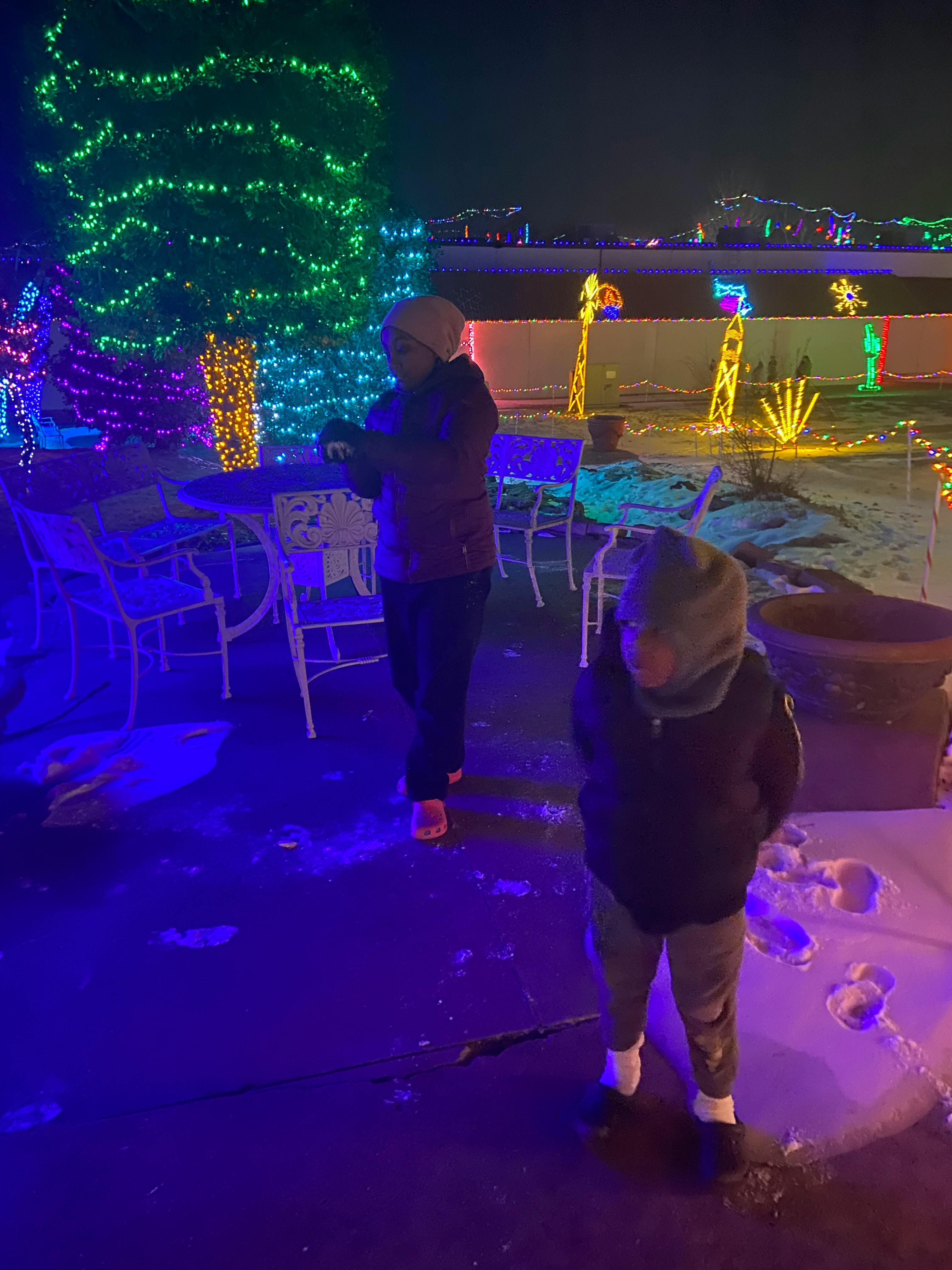 Two people standing outdoors at night surrounded by colorful lights