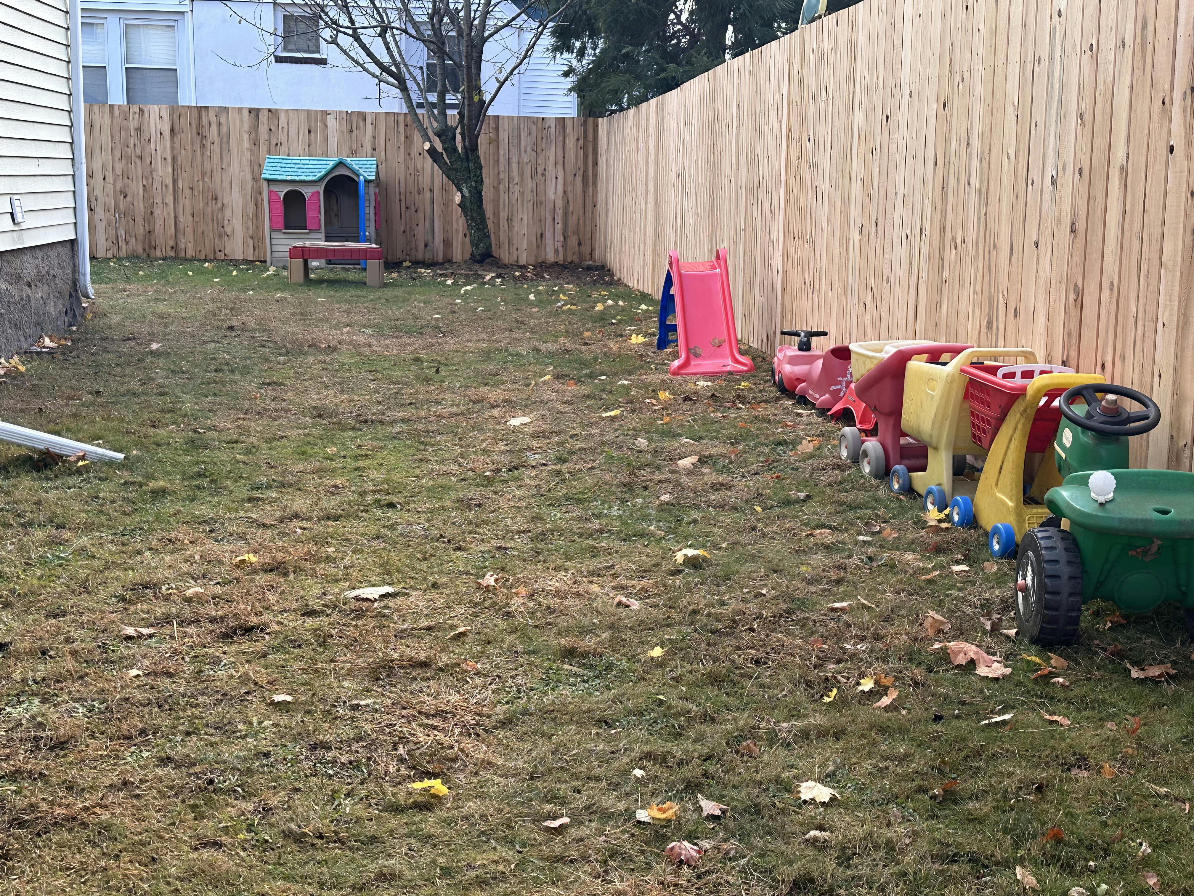 Backyard with a wooden fence, playhouse, slide, and toy train