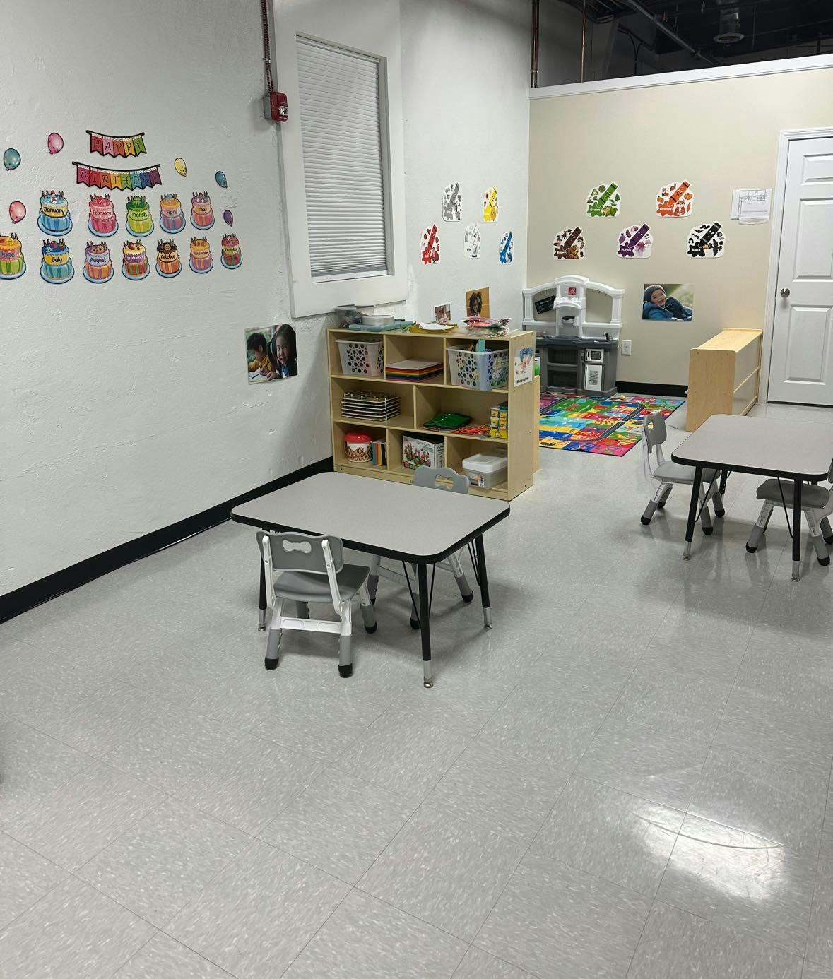 Classroom with small tables, chairs, and learning materials on shelves