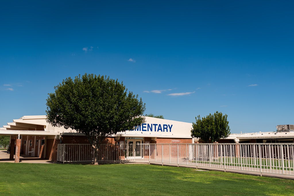 Building with "MENTARY" visible on its facade, green lawn, and trees