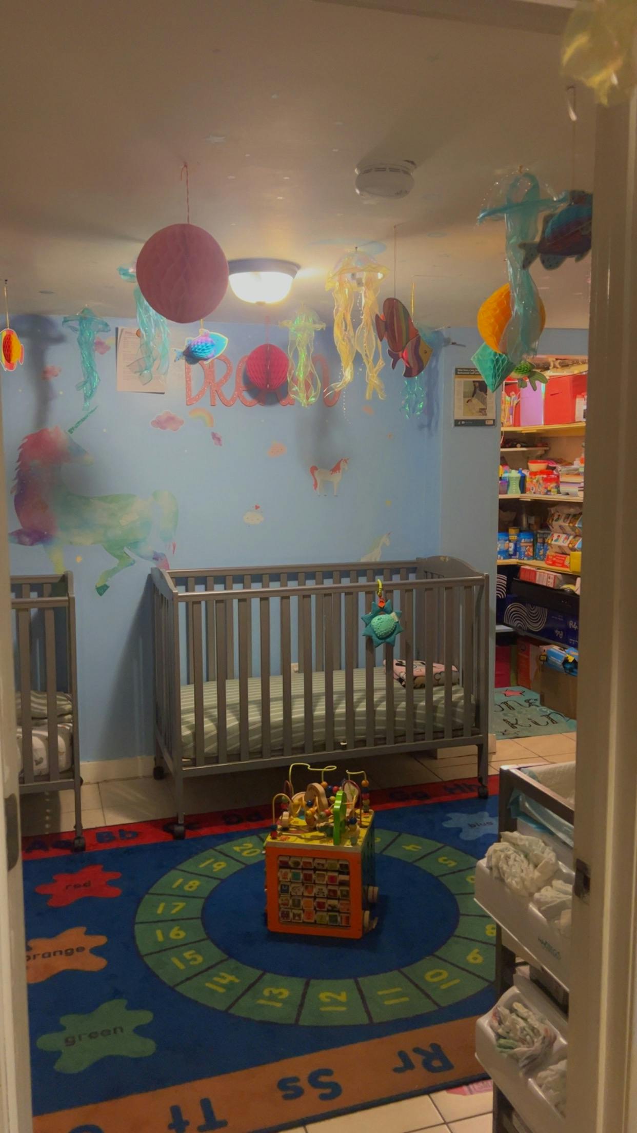 A nursery room with a crib, a play mat, and decorations