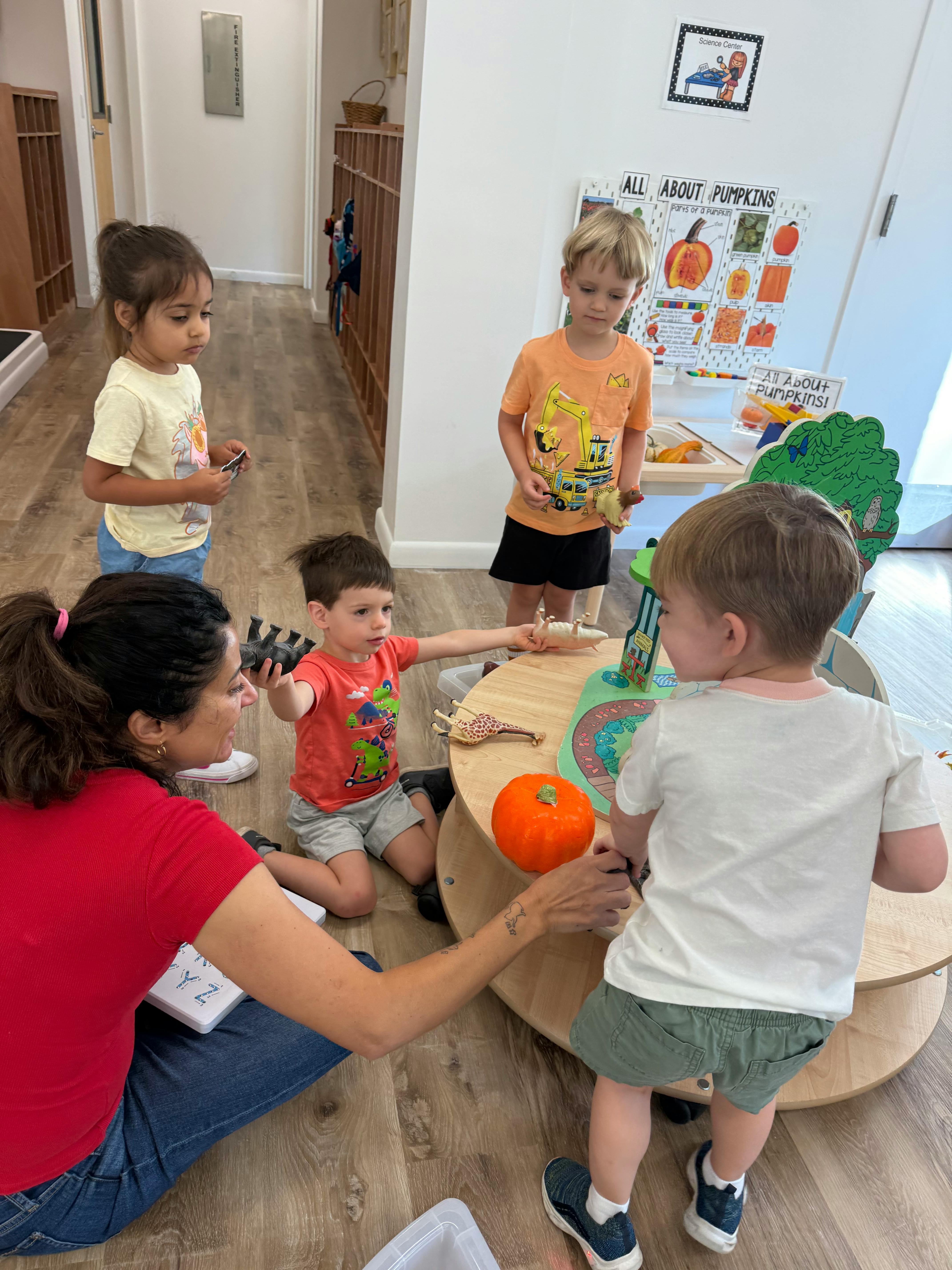 Adult and children interacting around a table with a pumpkin