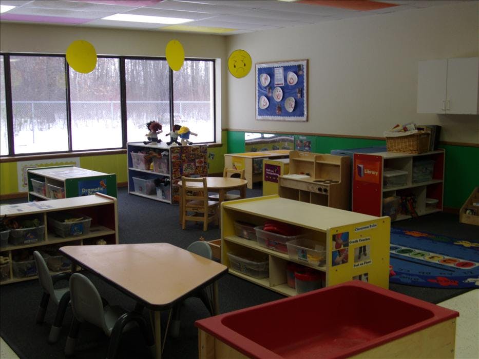 A colorful classroom with tables, chairs, and shelves full of toys