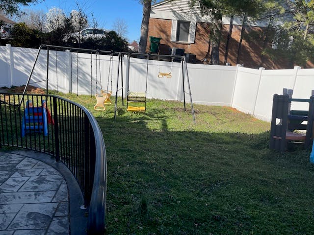 Backyard with a swing set and a white fence