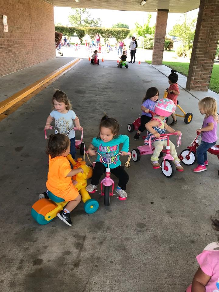 Children riding tricycles and other ride-on toys outdoors