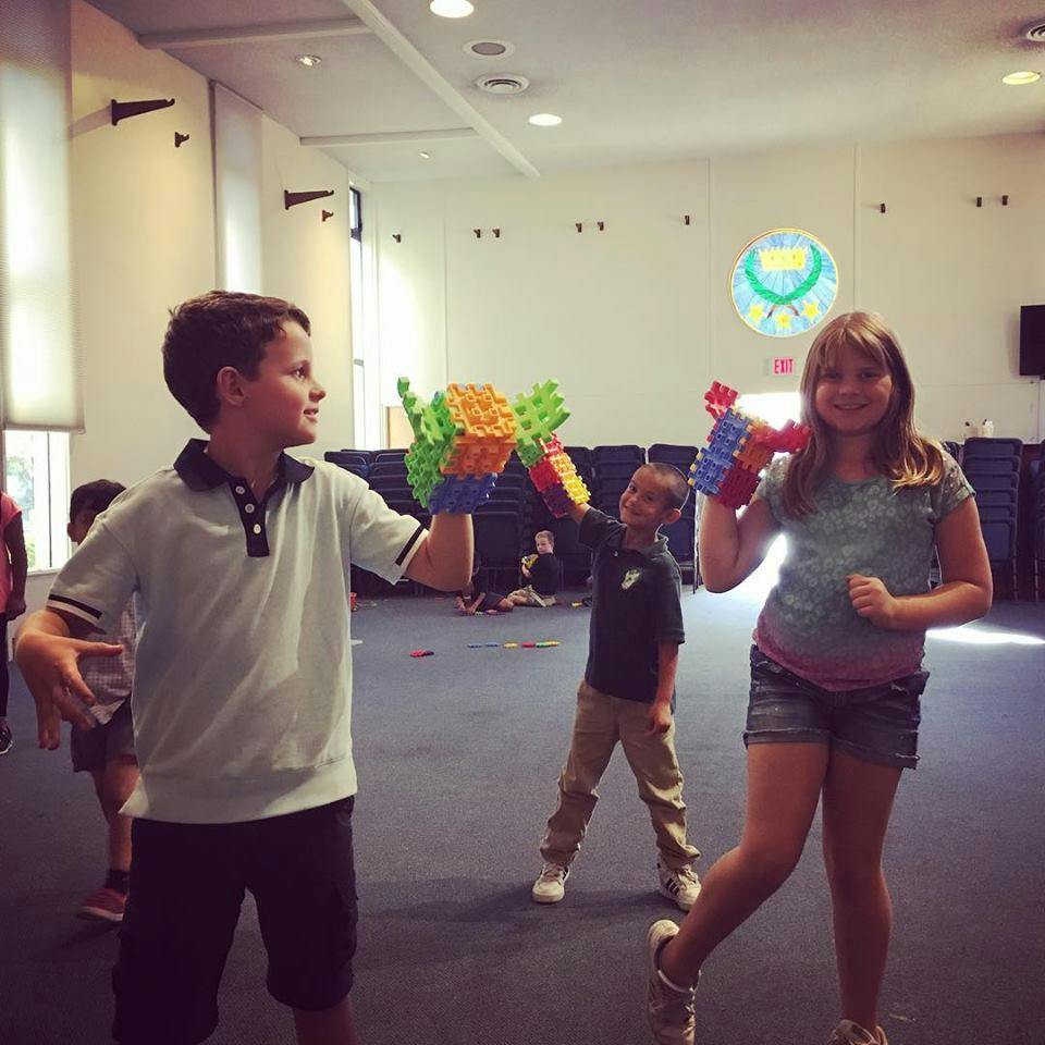Two children holding colorful block creations, another child in background