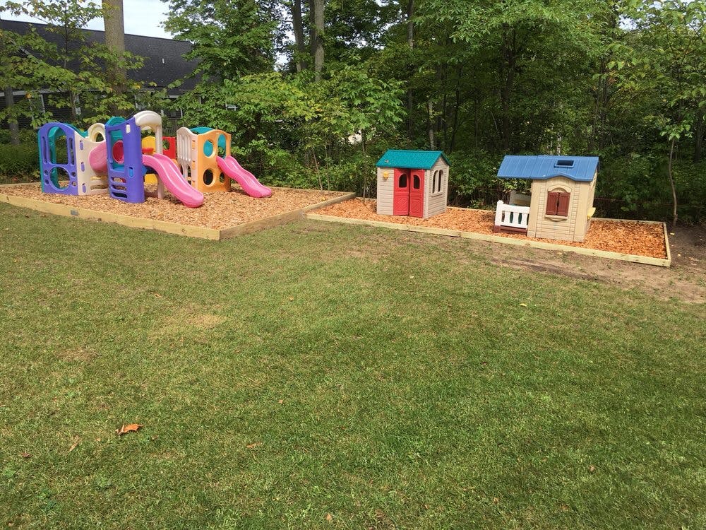 Playground with colorful slides and two playhouses on wood chips
