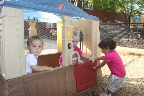 Three children playing in a playhouse on a playground