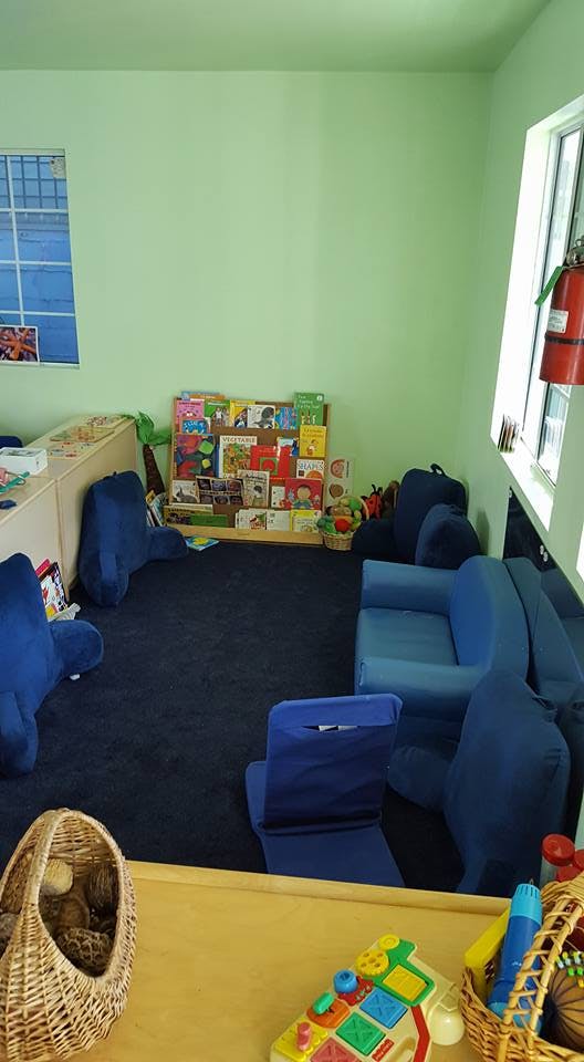 Children's play area with blue seating, a bookshelf, and toys