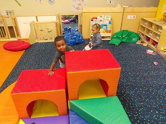 Two children playing with soft play blocks in a classroom