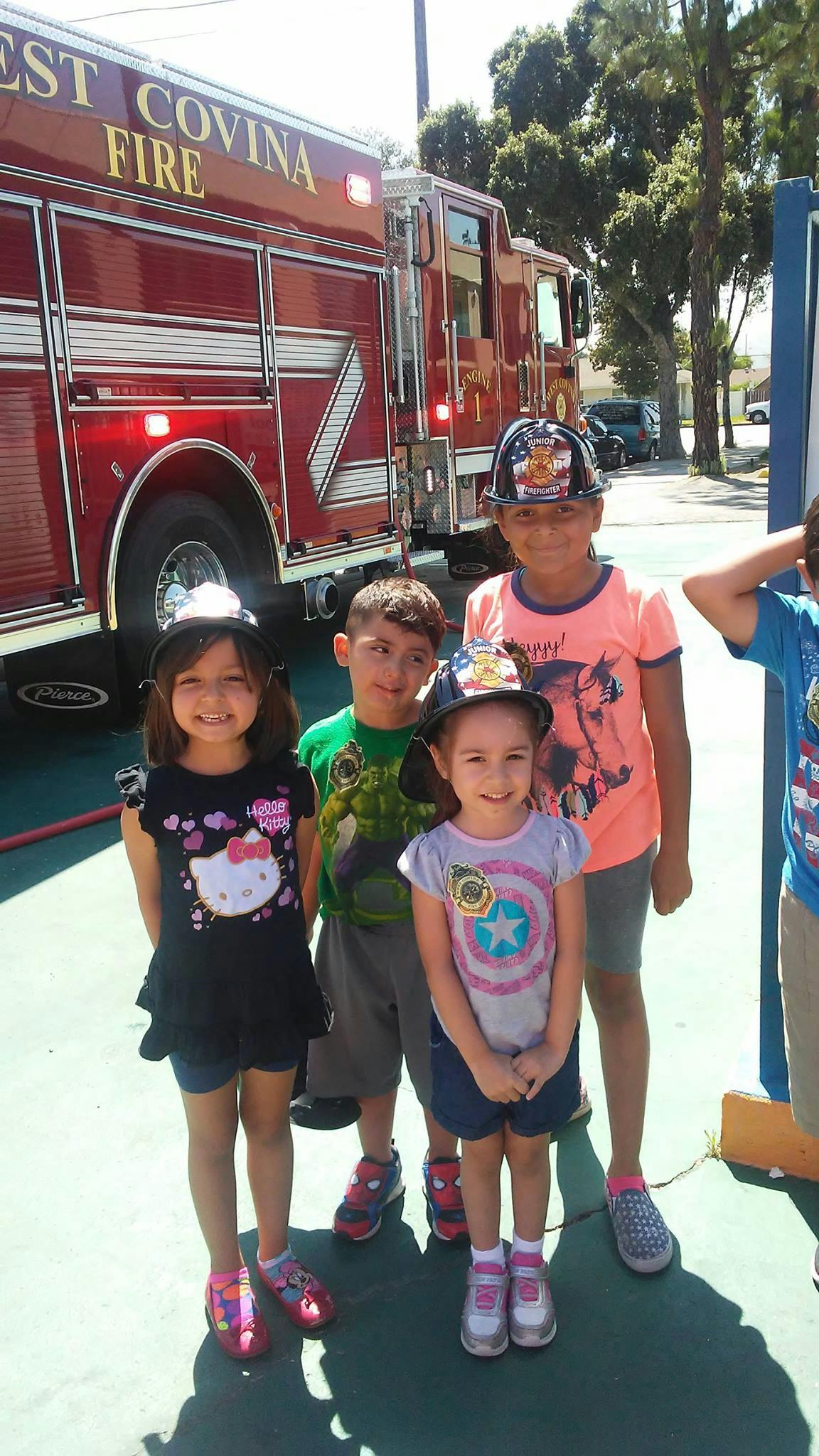 Children wearing fire hats standing in front of a fire truck