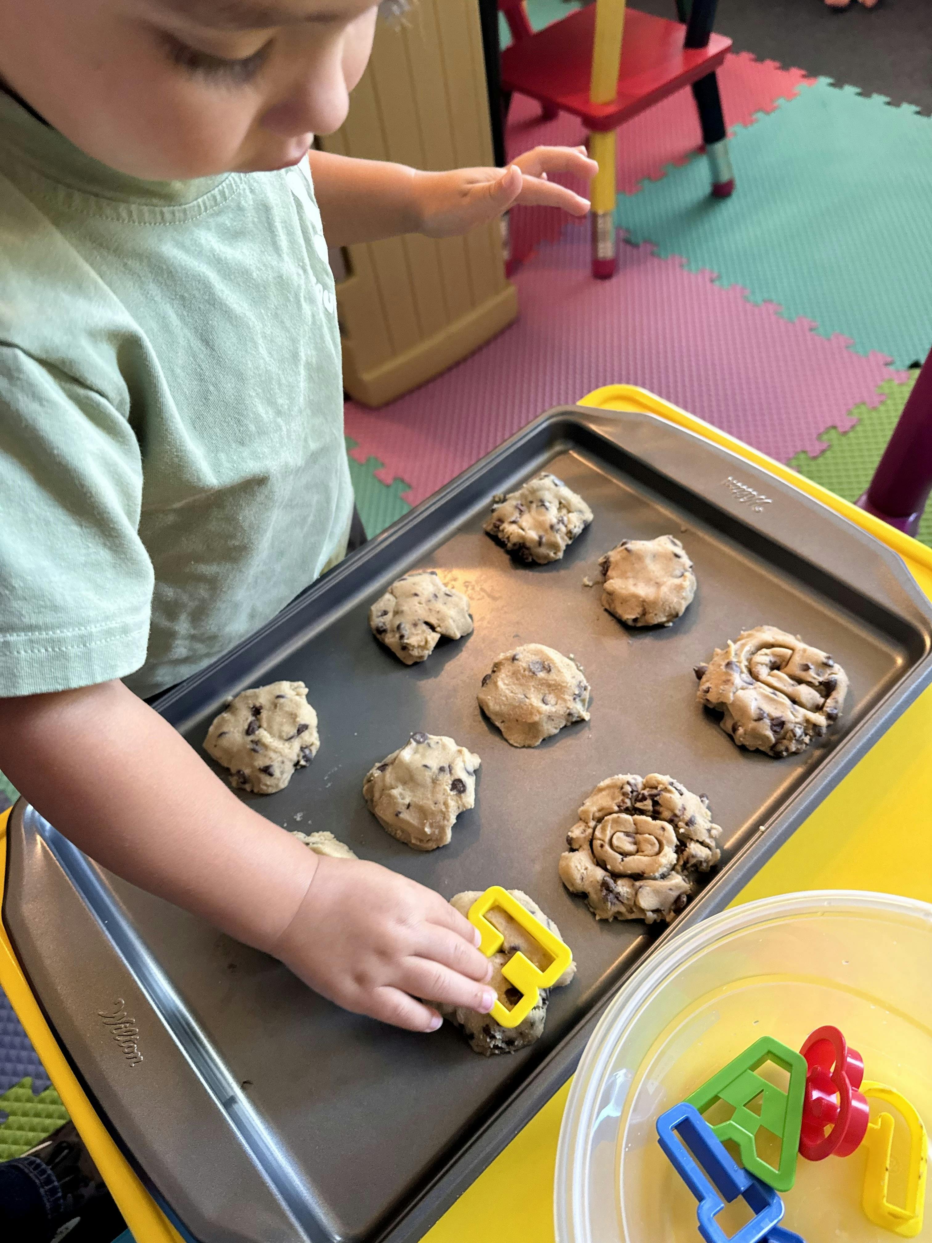 Child placing a cookie cutter on dough on a baking sheet