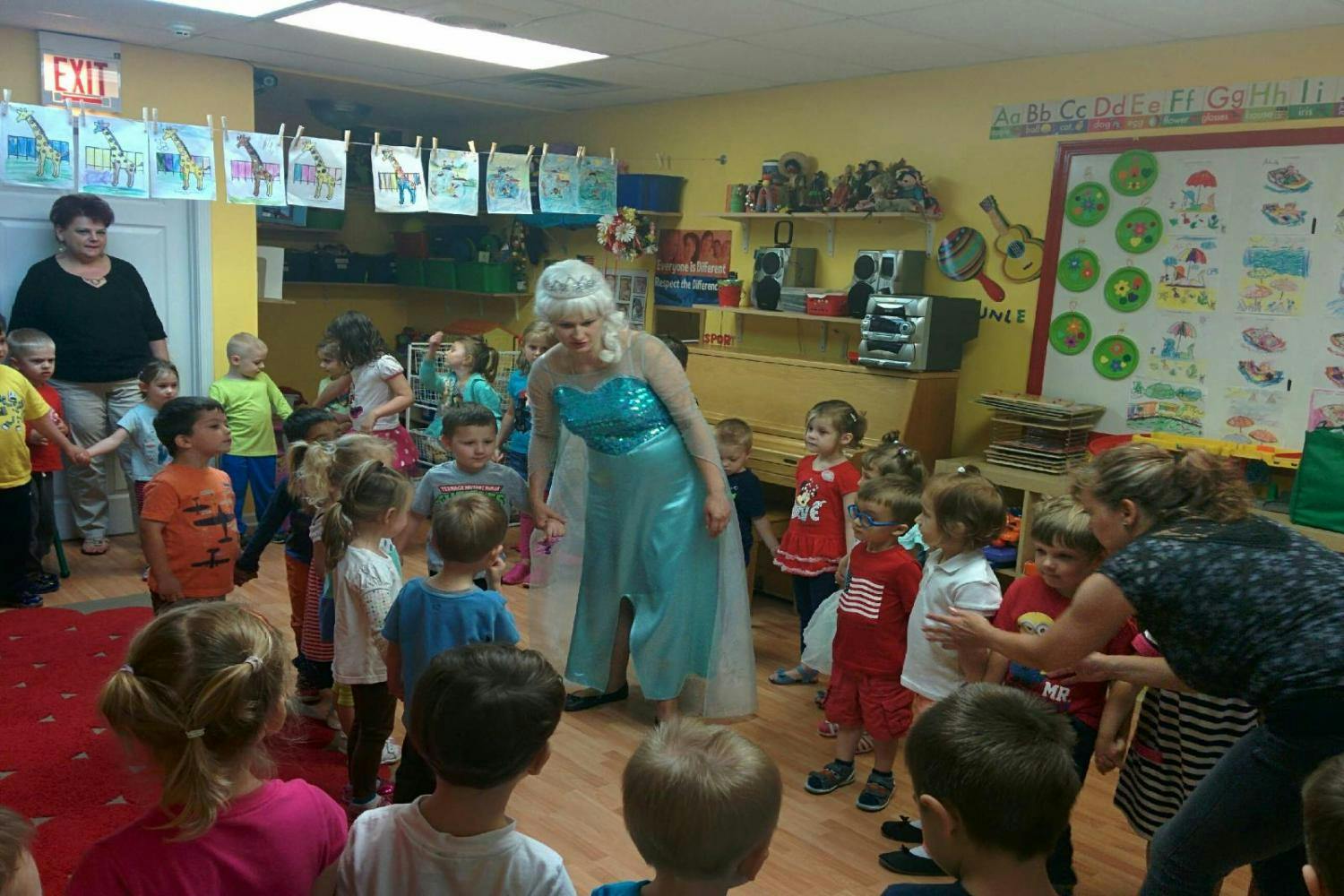 Person in blue dress and white wig interacting with children in a classroom