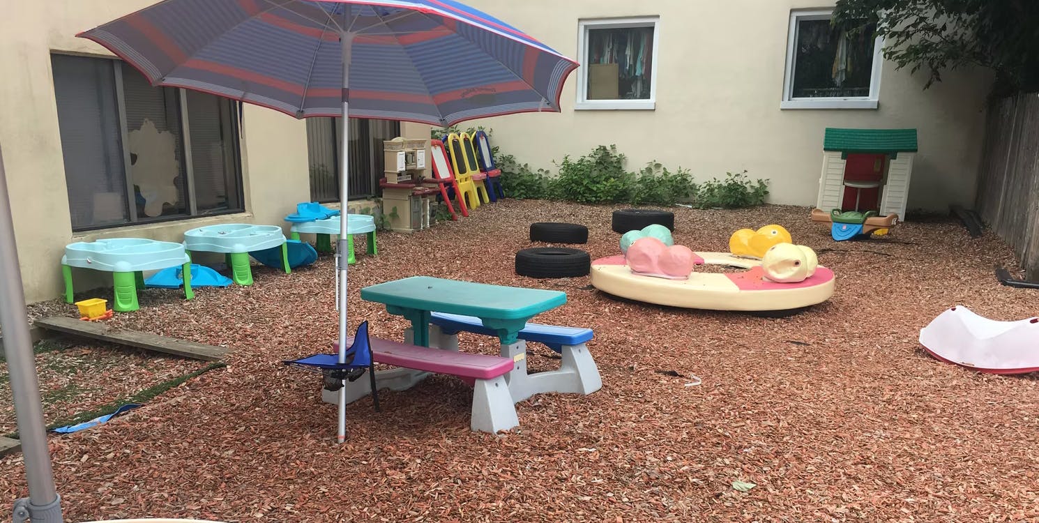 Outdoor play area with umbrella, picnic table, and various toys