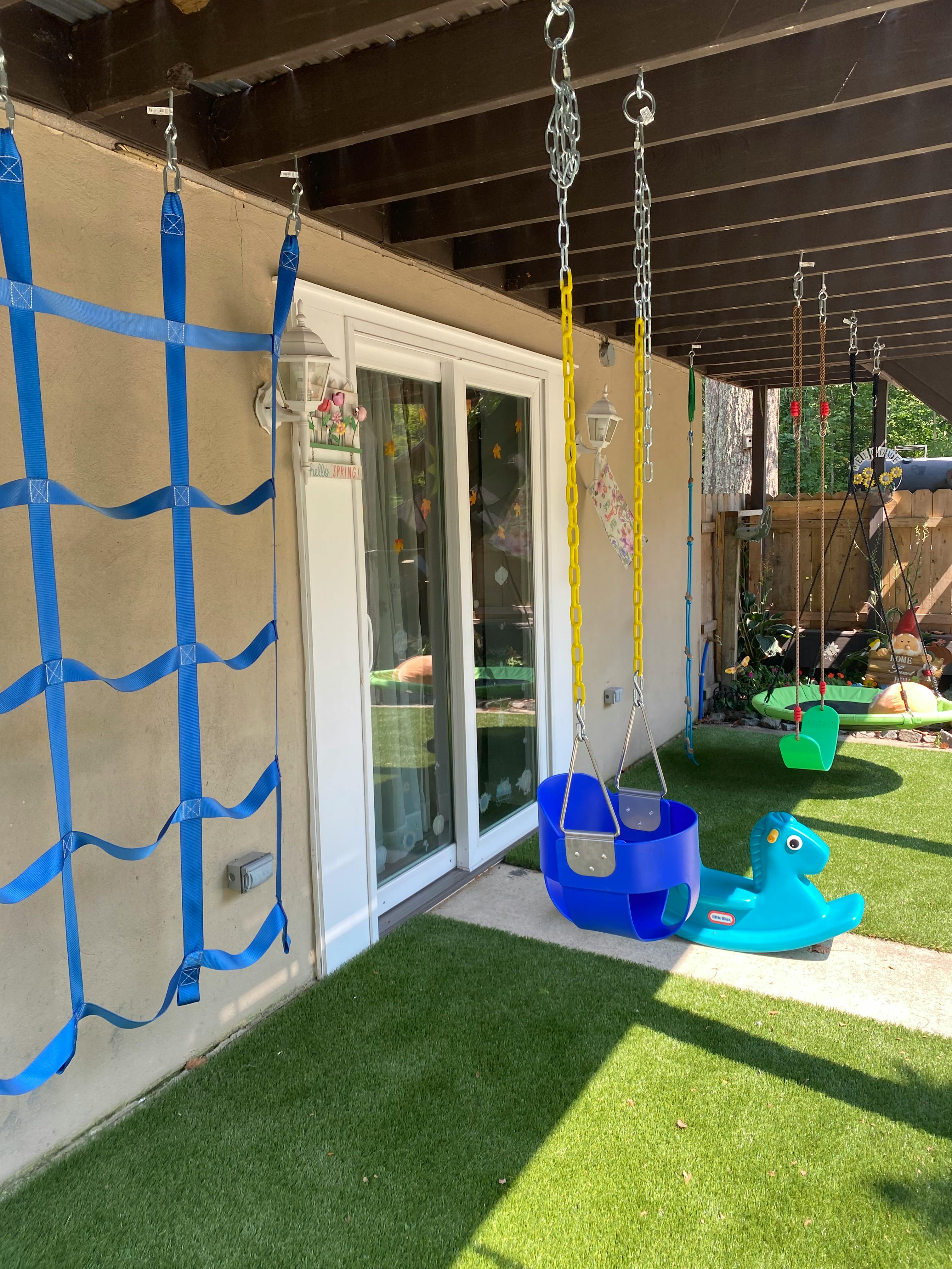 Blue child's swing and a blue rocking horse on artificial grass
