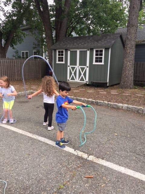 Three children playing with jump ropes outdoors