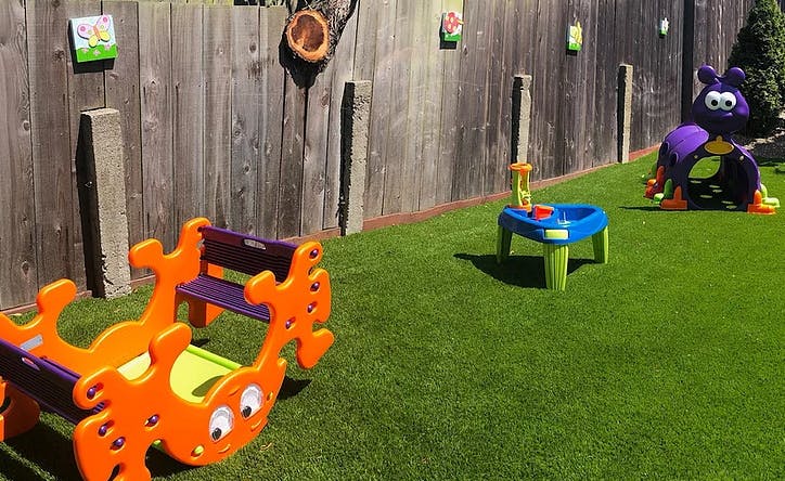 Playground with a rocking bench, water table, and purple bug toy