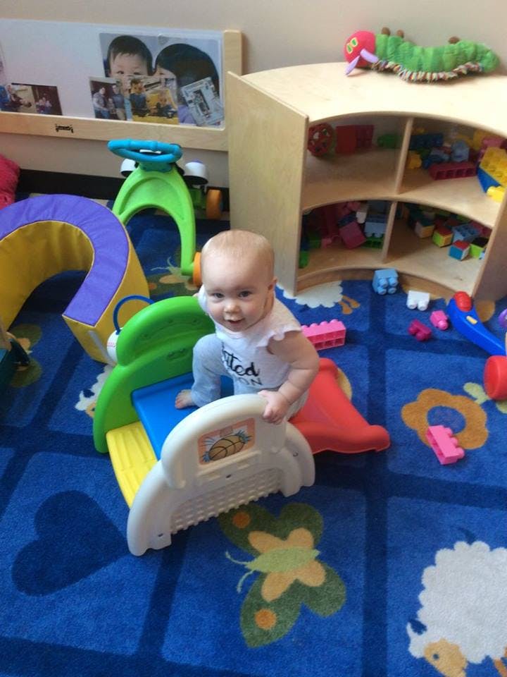 Child playing on a small slide in a room with toys