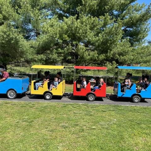 People and children riding in a colorful trackless train