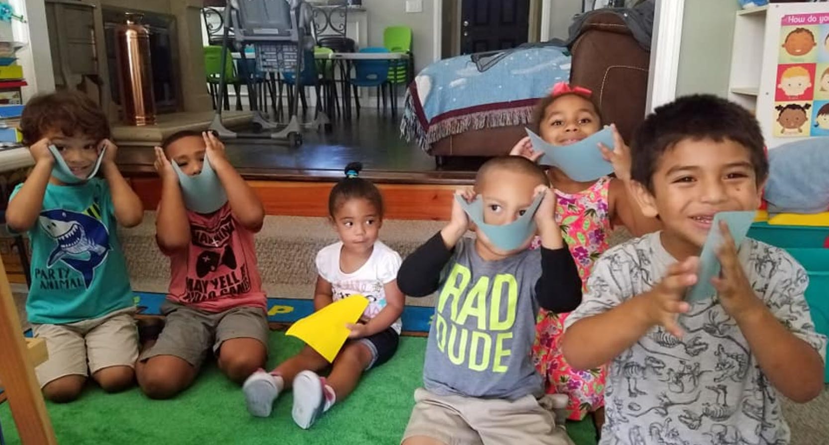 Group of children holding blue masks to their faces