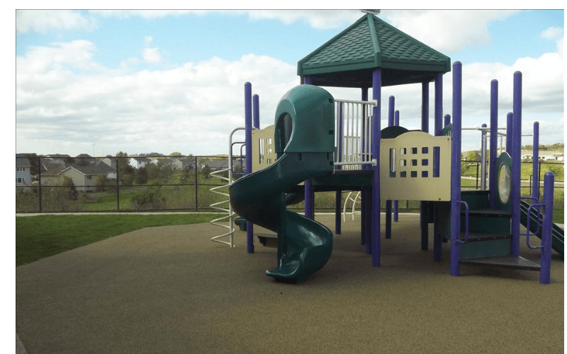 A playground with a green and purple structure and a spiral slide