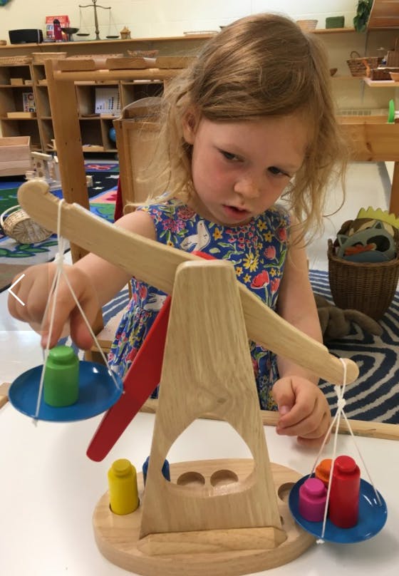 Child playing with a wooden balance scale