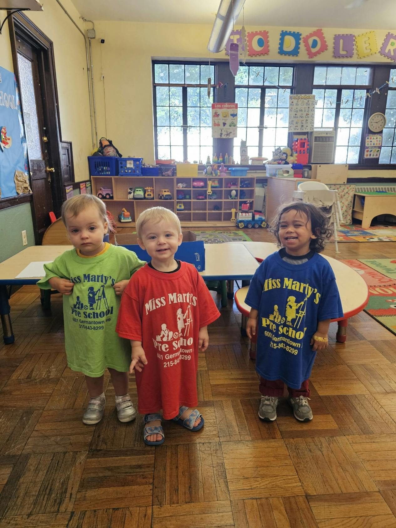 Three children wearing matching t-shirts in a classroom