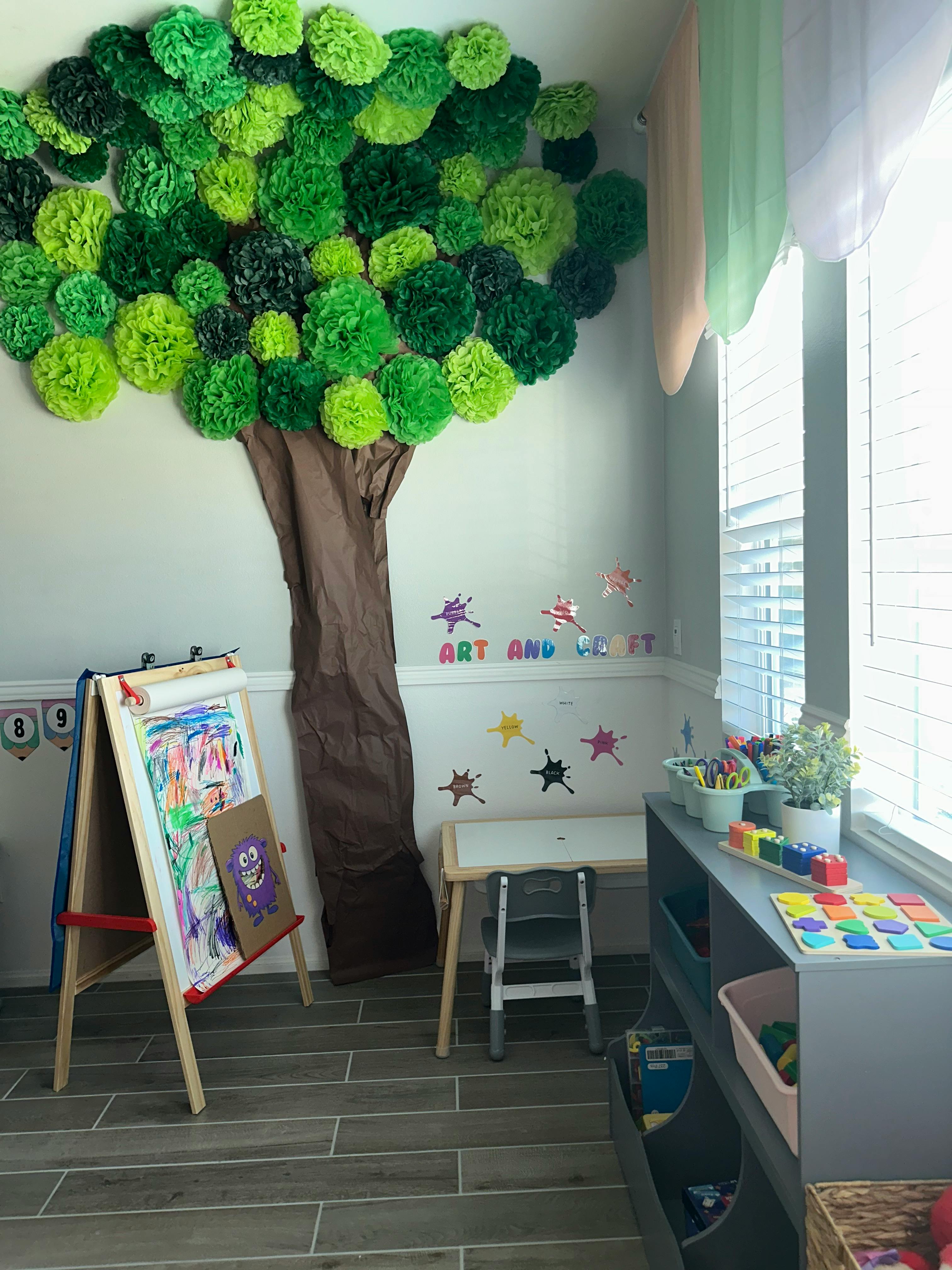 Art and craft area for children with a paper tree decoration and easel