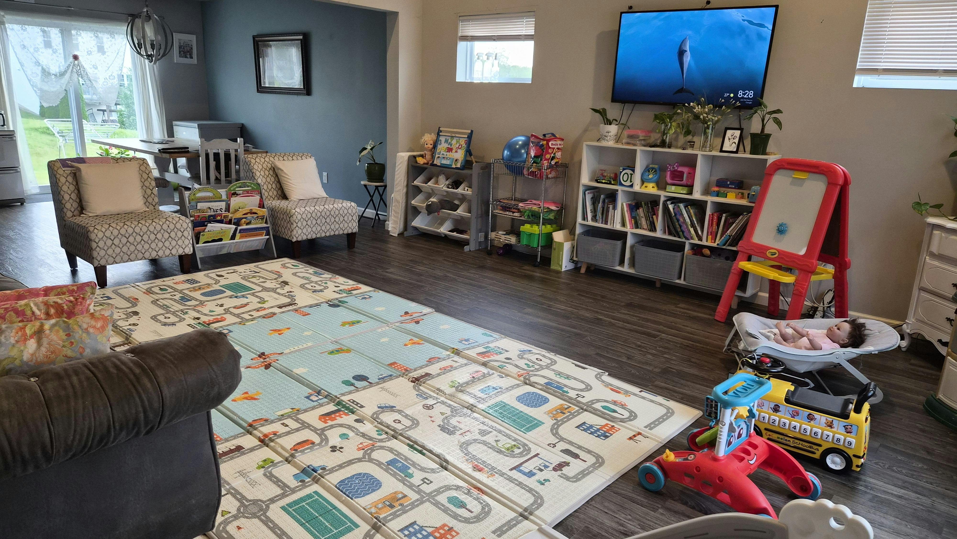 Living room with a baby on the floor, toys, and a TV showing a dolphin