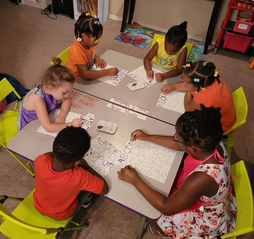 Adult and children sitting at a table doing an activity