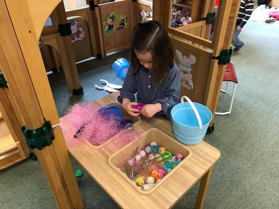Child playing with colorful objects at a wooden table