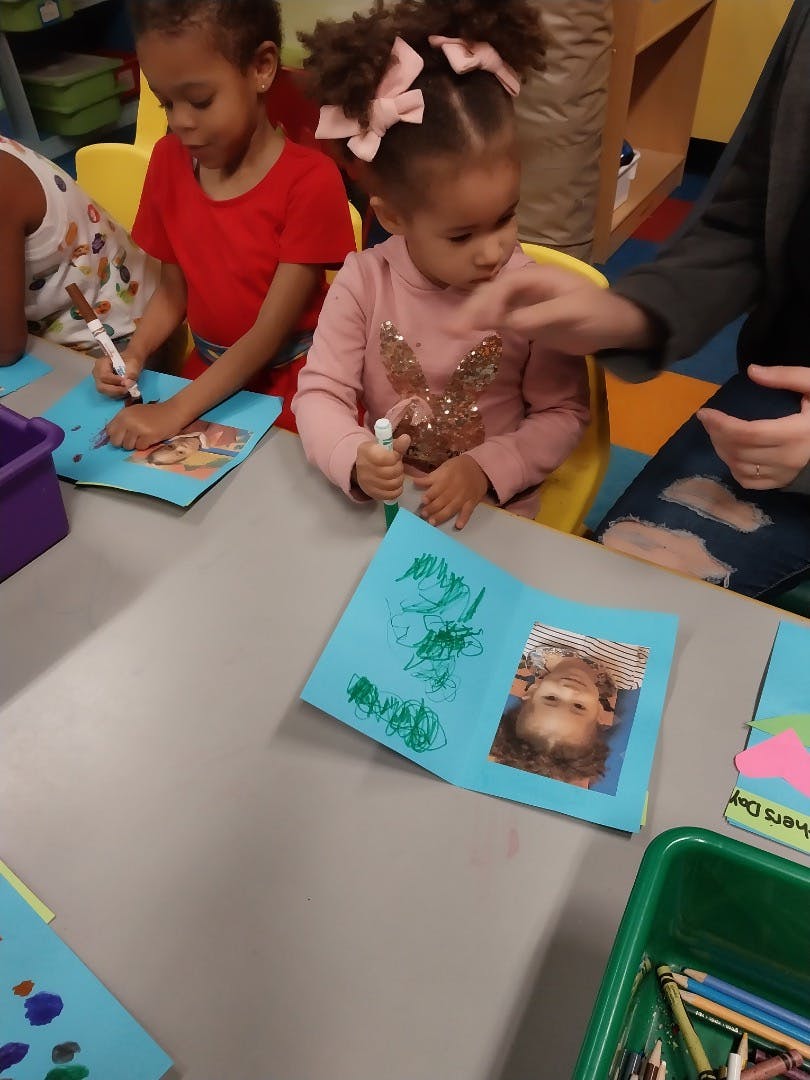 Children drawing on paper cards with markers at a table