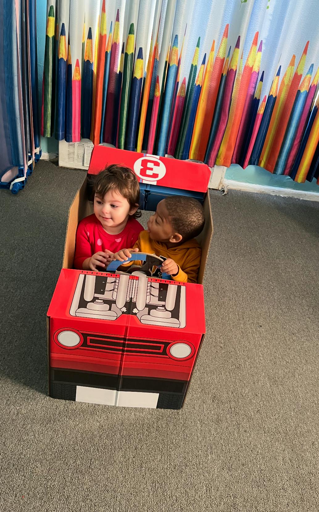Two children sitting in a cardboard box car