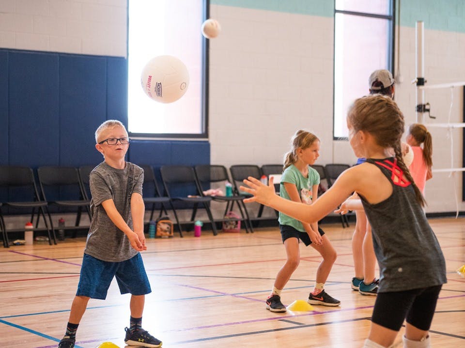 Children playing volleyball in a gym