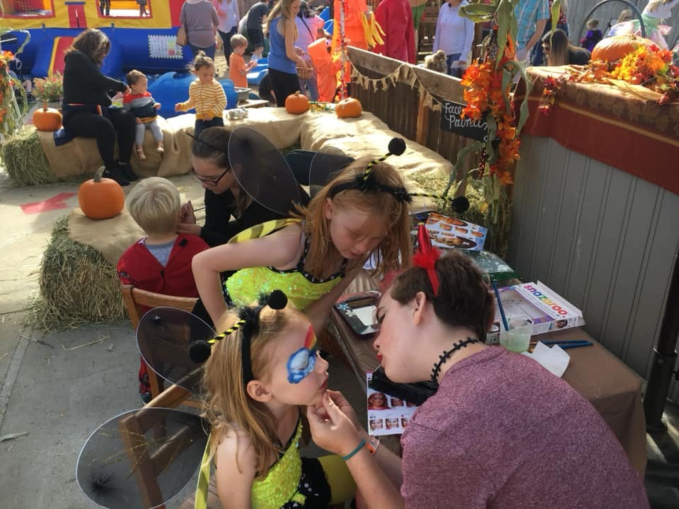 Person painting a child's face at an outdoor event