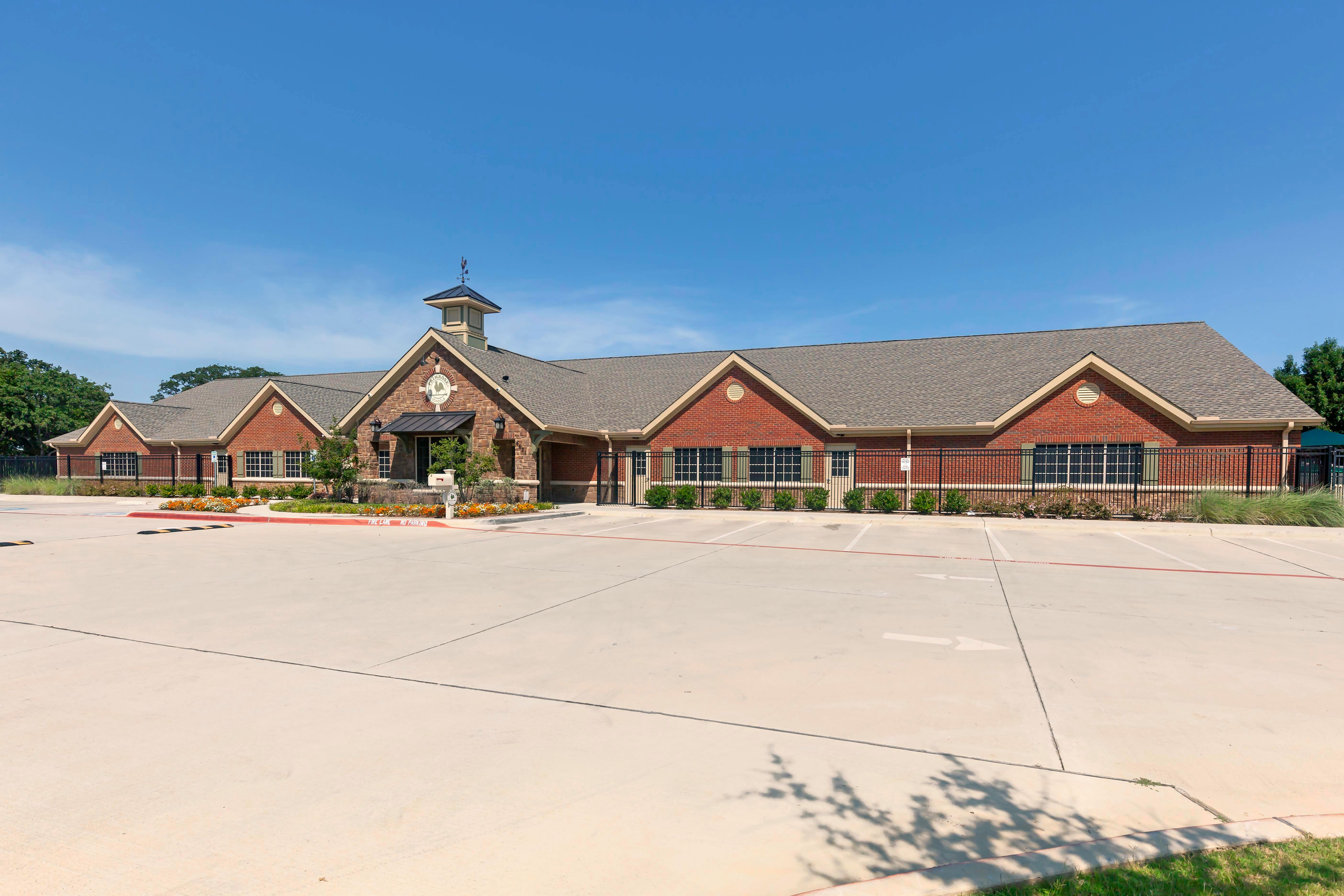 Building with brick and stone facade, cupola, and adjacent empty parking lot