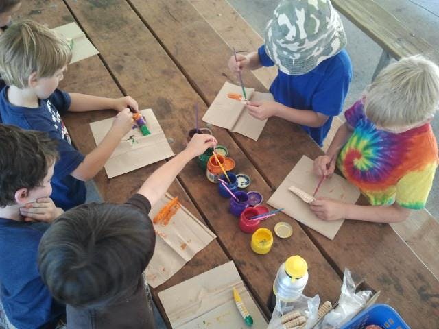 Children painting at a wooden table
