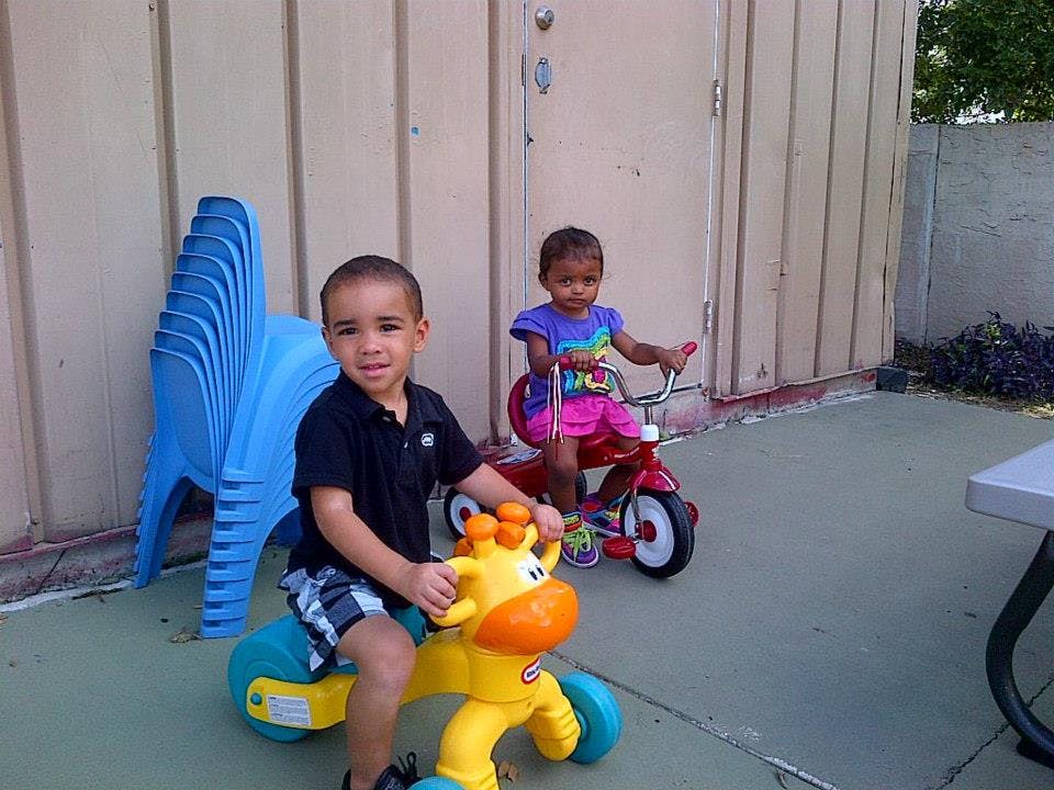 Two children playing with ride-on toys outdoors