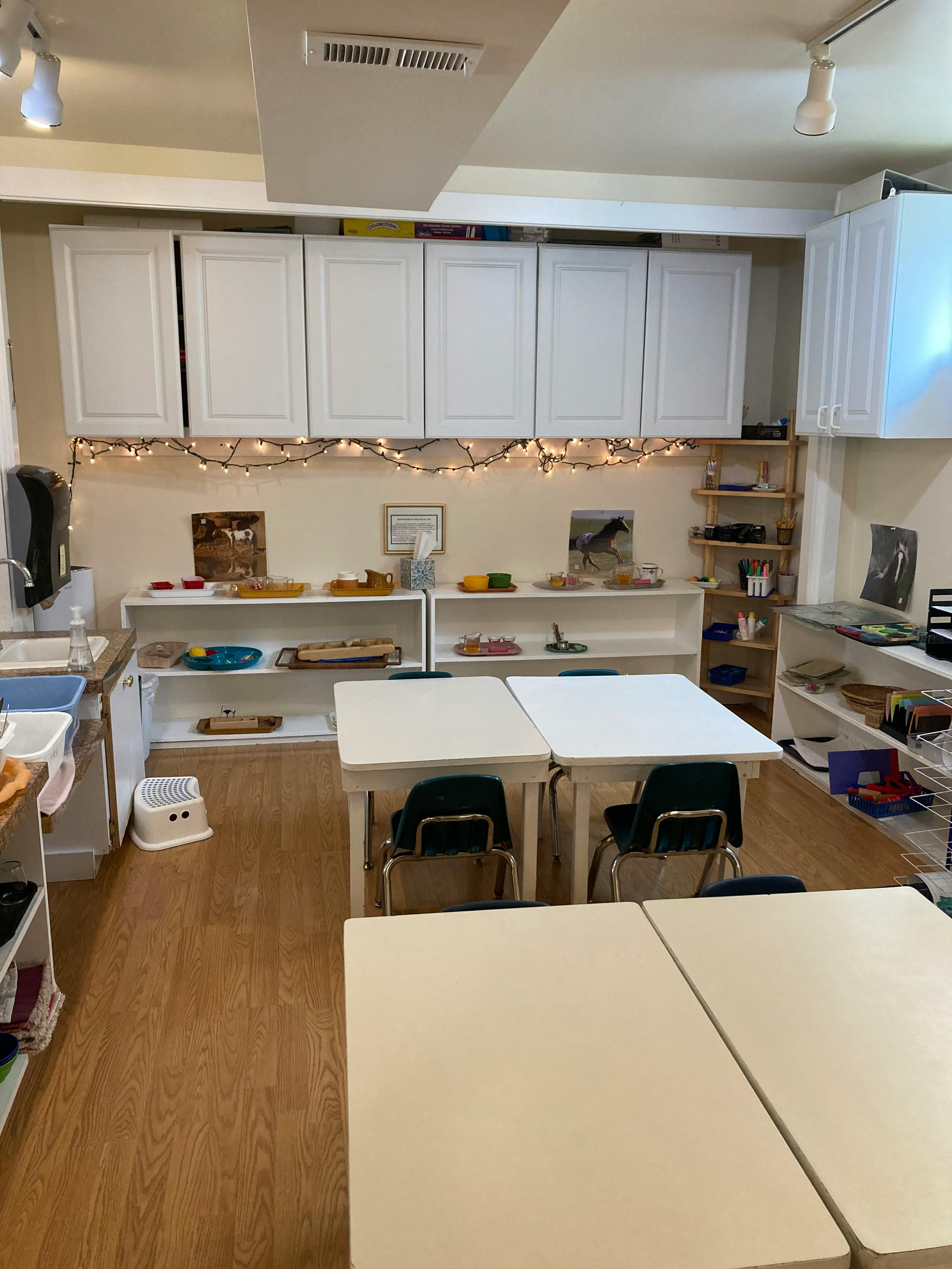 Classroom with tables, chairs, and shelves with learning materials