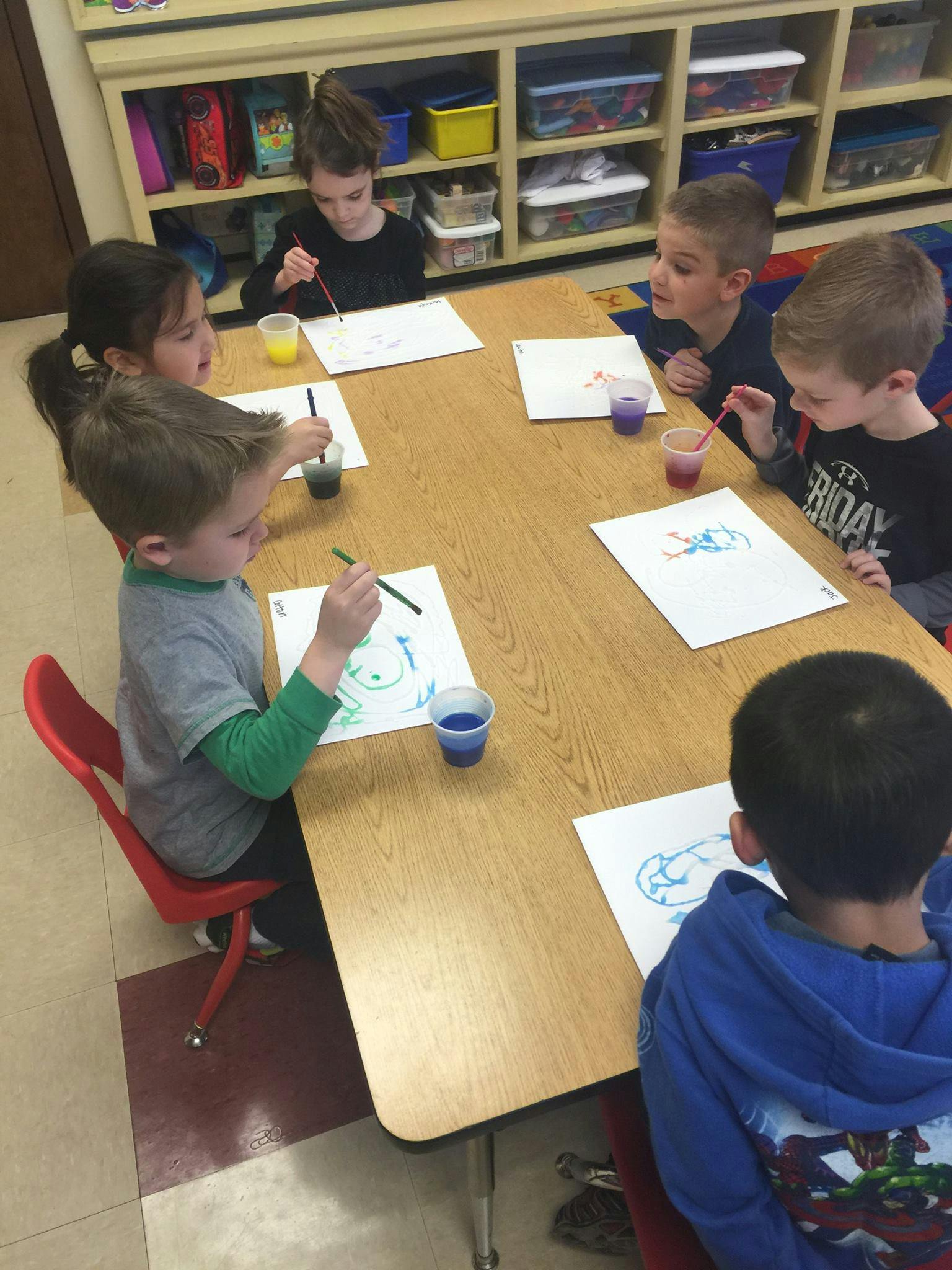 Children painting at a table in a classroom