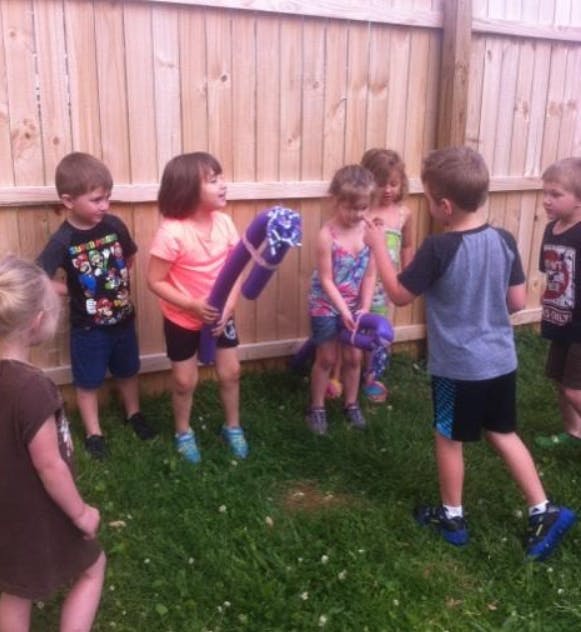 Children playing with purple objects in a grassy area