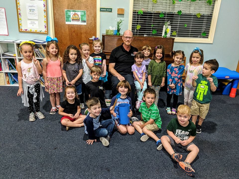 Adult and group of children posing for a photo in a classroom