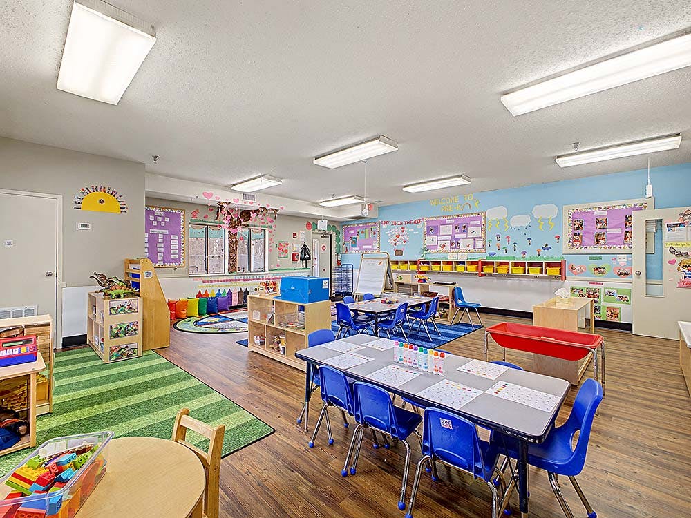 Classroom with small tables and chairs, shelves, and decorations on the walls