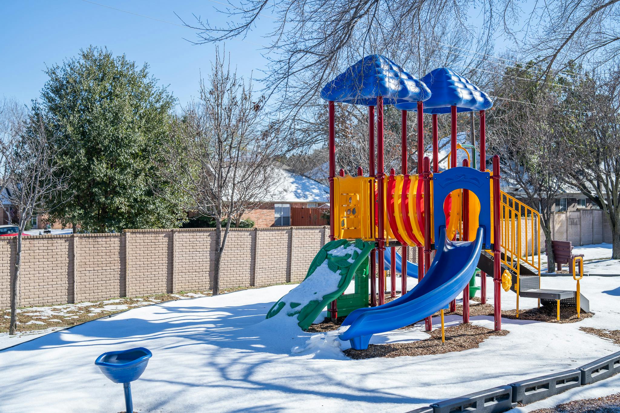 Colorful playground equipment covered in snow in a residential area