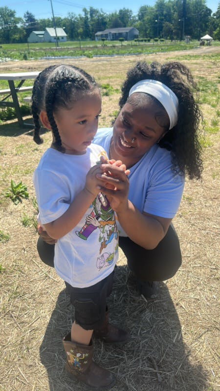 Adult person crouching and holding the hands of a child outdoors