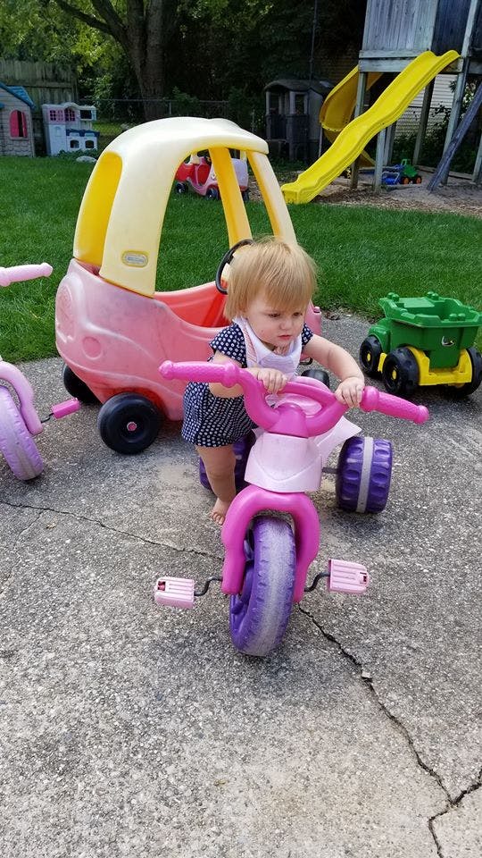 Child on a pink tricycle outdoors