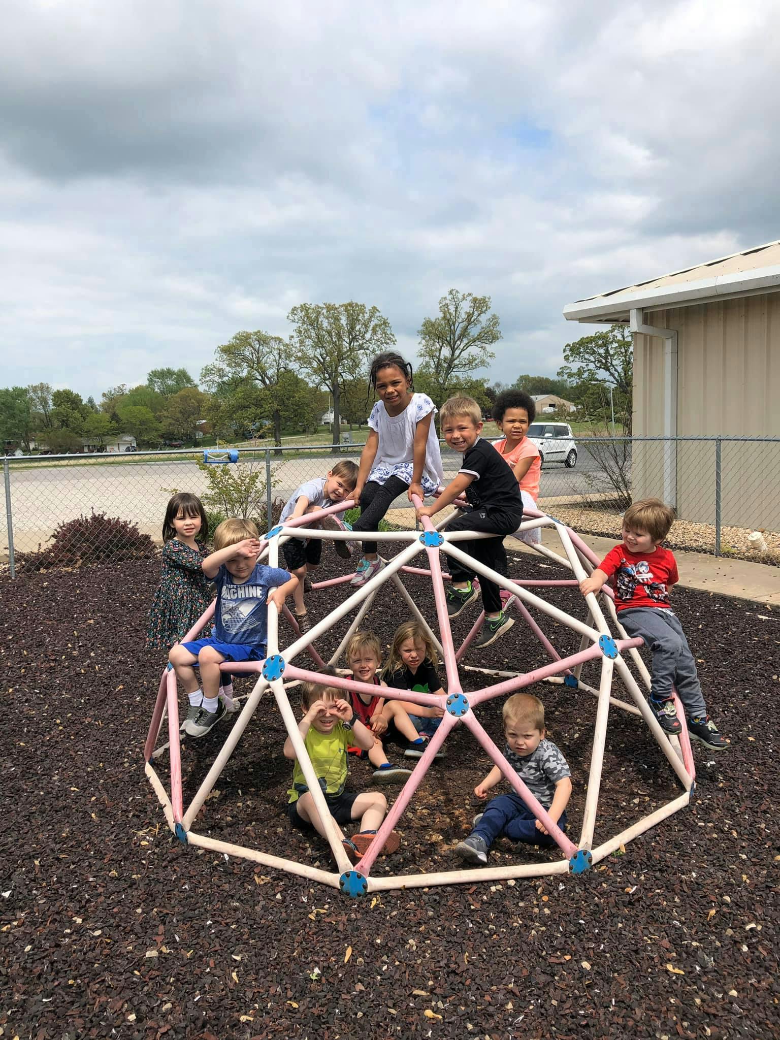 Children playing on a geodesic dome climber on a playground